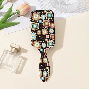 Detailansicht der schwarzen Haarbürste mit Retro-Blumenmuster und praktischem Aufhängeloch