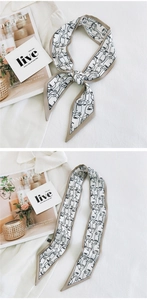 Detail of long white silk scarf with black face line art tied in a bow and flat layout