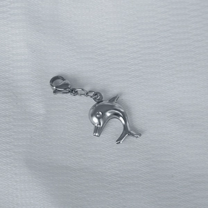 Polished silver dolphin charm with lobster clasp on grey textured background