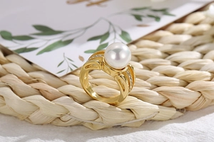 Detailed macro view of a gold plated pearl ring with small diamonds on a woven mat