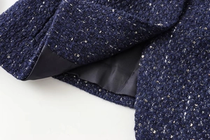 Detailed view of navy blue tweed fabric with gold and silver sequins and satin lining