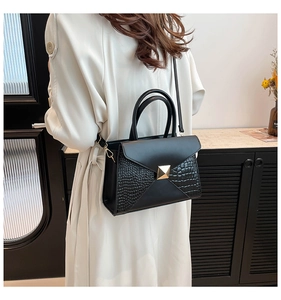 Close-up of black crocodile pattern leather tote with golden buckle and sleek handle