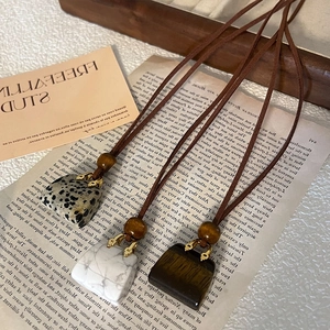 Detail of stone pendant necklace with brown leather cord on a vintage background