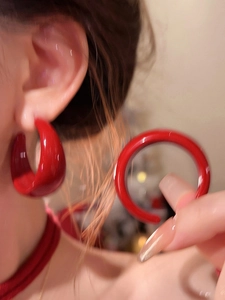 Gros plan d'une personne portant une boucle d'oreille créole rouge en acrylique de style rétro