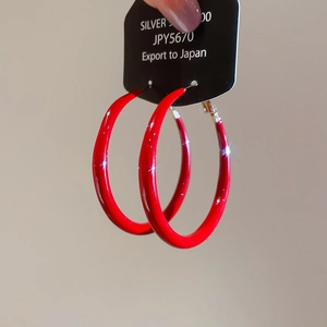 Macro detail of red glossy hoops on silver 925 card showing minimalist elegant earring design