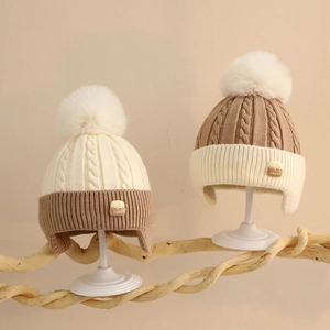 Close-up of knit baby winter hats with fluffy faux fur pom-poms and ear protection
