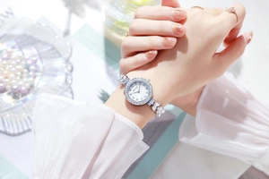 Close-up of women's silver watch with rhinestone mermaid dial and elegant crystal bezel