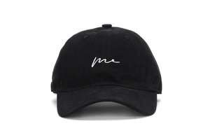 Close-up of white 'me' script embroidery on a black cotton baseball cap surface