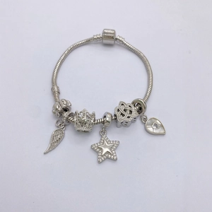 Silver snake chain bracelet featuring sparkling star, crown, and wing charms pendants