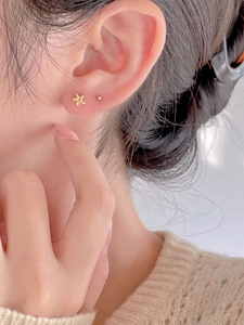 Close-up of a model wearing minimalist golden flower and ball 925 silver stud earrings