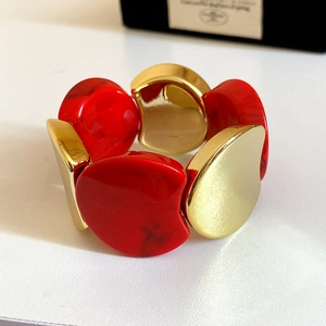 Macro shot of chunky red marble resin and gold metal plate elastic bracelet