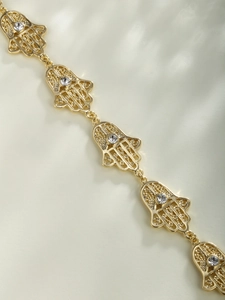 Gros plan d'un bracelet main de Fatma doré avec maille évidée et incrustation cristal