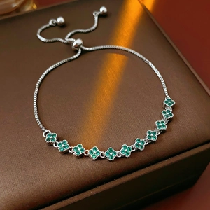 Detail of adjustable silver bracelet with sparkling emerald green clover charms in zircons