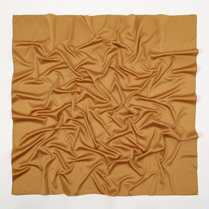 Detailed view of golden satin silk fabric texture with soft drapes and elegant matte luster