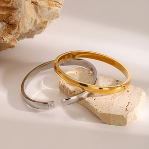 Detailed view of polished gold and silver stainless steel bangles on natural stone