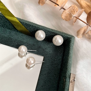 Detail of round white pearl earrings with silver needles in green velvet jewelry box