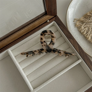 Macro detail of leopard print resin hair claw clip displayed in a wooden jewelry box