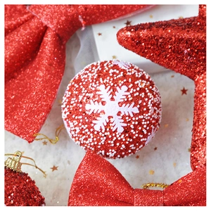 Close-up of red glitter bow and star ornaments with white snowflake Christmas ball