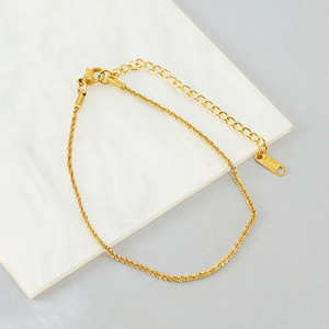 Close-up of 18K gold plated stainless steel anklet with S.STEEL tag on marble surface