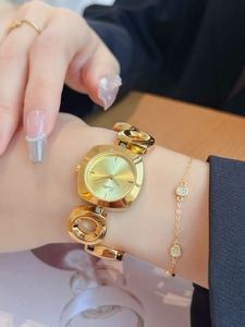 Elegant gold women's watch featuring a link bracelet and square champagne dial on wrist