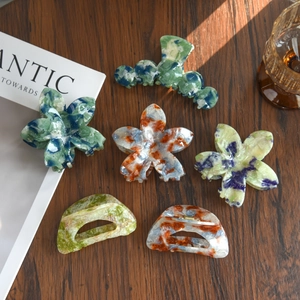 Fresh floral and marble pattern hair claw clips set on a wooden surface for women
