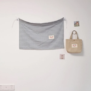 Detail of checkered car window curtain with beige corduroy bag and smiley face labels