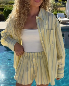 Outdoor poolside view of a women's yellow and blue striped shirt and shorts set