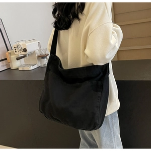 Black canvas tote bag showing spacious side pocket and comfortable wide strap on shoulder