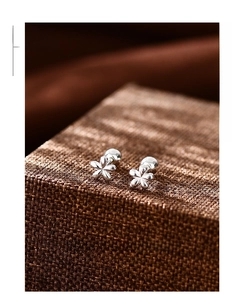 Vista macro de pendientes minimalistas de plata S999 con forma de flor de cinco pétalos finos