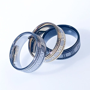 Detail of three stainless steel rings with Roman numerals in silver, gold, and black