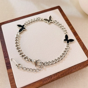 Close-up of stainless steel chain bracelet with black acrylic butterfly charms and lobster clasp