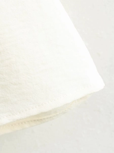Detailed close-up of high-quality white cotton fabric showing neat stitching and fine texture