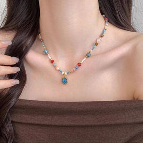 Détail du collier de perles colorées avec pendentif ovale bleu vintage sur la clavicule