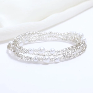 Detailed view of silver glass beads and white faux pearls layered on a summer beach waist chain