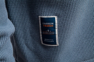 Macro detail of blue waffle knit fabric texture and rectangular fashion trends label