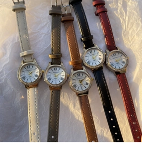 Flat lay of multiple leather strap watches with rhinestone bezels and Roman numeral dials