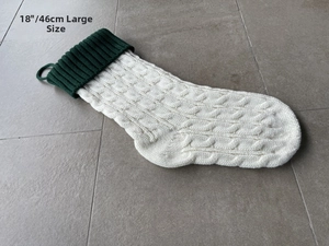 Detail of 18 inch large knitted Christmas stocking with green cuff and white cable pattern
