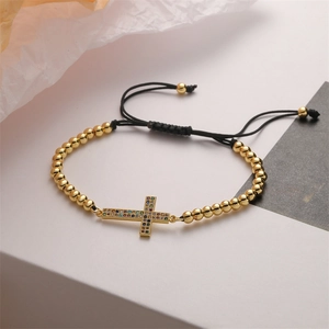Detailed macro view of gold cross pendant with colorful zircon on adjustable black cord