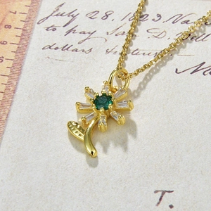 Detail of sunflower necklace with green gemstone heart and clear crystal petals