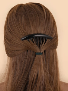 Close-up of black plastic hair comb clip worn on brown hair showing styling effect