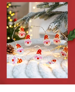 Close-up of Santa Claus LED string lights hanging from snowy pine branches with warm glow
