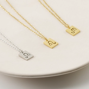 Three square zodiac sign necklaces in gold and silver finish with engraved symbols