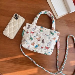 Detail of white quilted canvas bag with colorful dog prints and woven rope strap