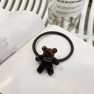 Detailed view of handmade amber bear hair tie with Amy Bear logo on an open book