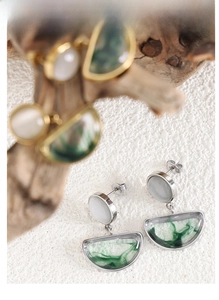 Detail of silver drop earrings with white stone and green ink-textured resin pendant