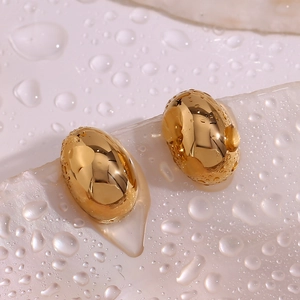 Dettaglio macro di orecchini a bottone a forma di fagiolo in oro 18K su pietra con gocce d'acqua