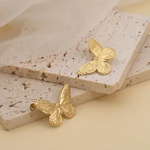 Elegant gold titanium steel butterfly stud earrings displayed on stone props
