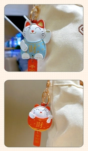 Close-up of cute cartoon lucky cat leather keychain charms with gold metal hooks