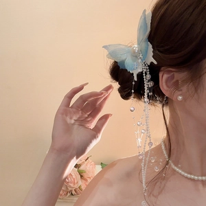 Detail of blue mesh butterfly hair clip with elegant pearl tassels on a model