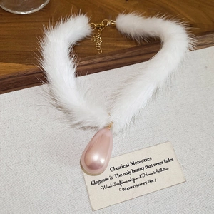 Detailed macro view of white plush collar necklace with a pink teardrop pearl pendant